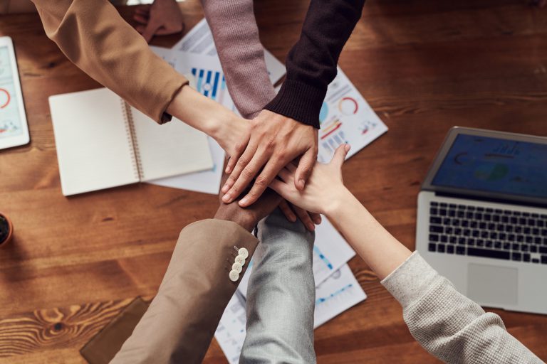 Six people stacking their hands together as a team.